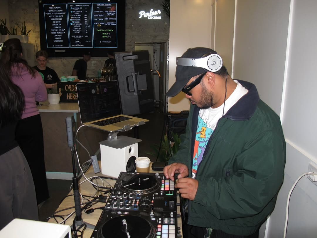 DJ playing inside the ice-cream shop while the crowd talks around the counter