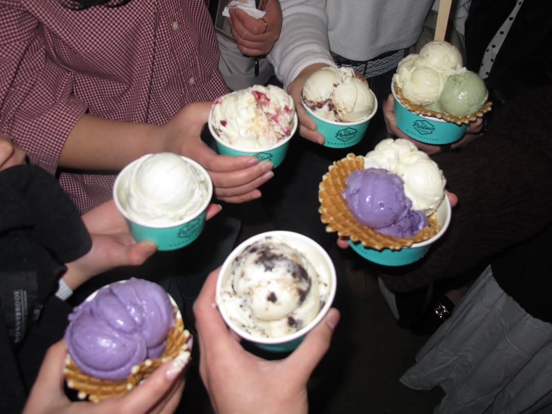 A circle of hands holding cups of ice cream together over the table