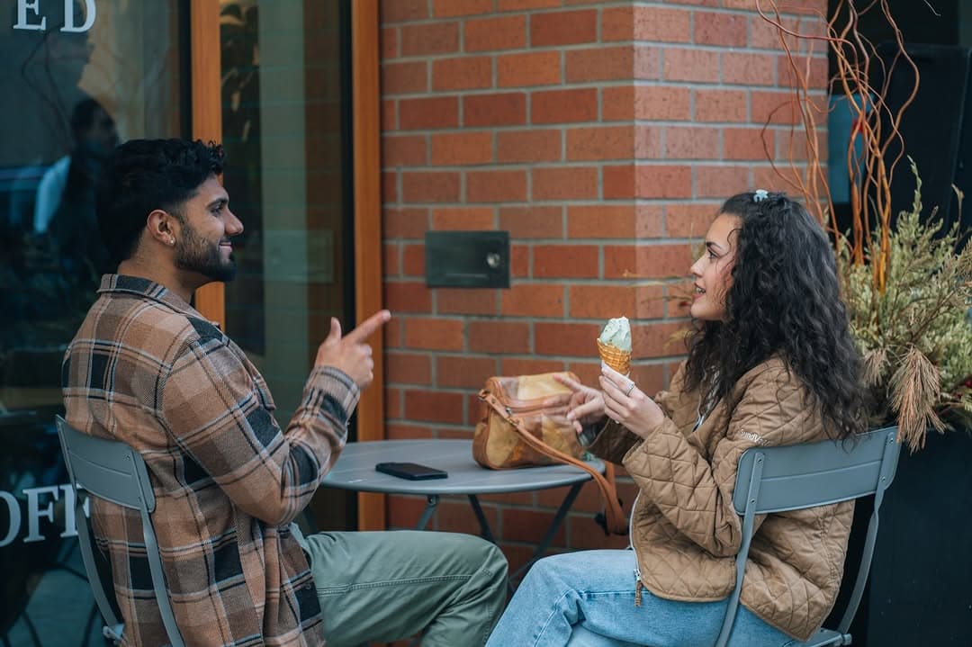 Two strangers deep in conversation at a little table by the brick wall