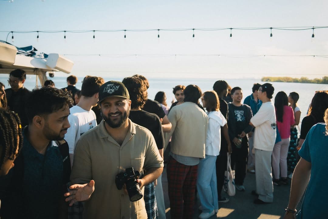 The yacht deck strung with lights as guests board at golden hour